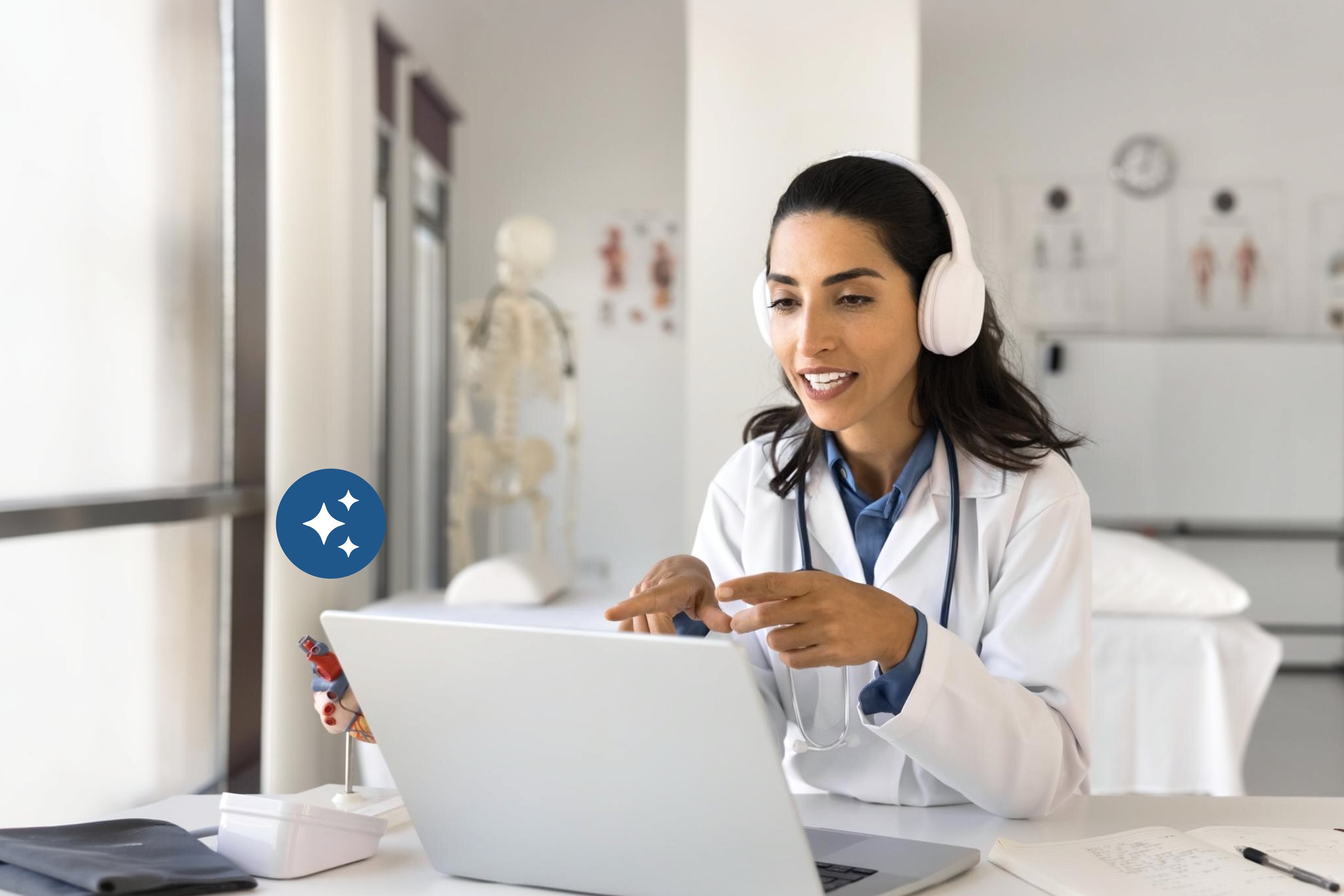 Female physician with headphones running a telehealth visit on her laptop in the exam room &mdash; eCareAssist hybrid care platform handles both virtual and in-person appointments